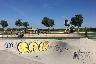 Ein BMX-Rad-Fahrer springt mit seinem Rad im Skatepark in die Höhe.